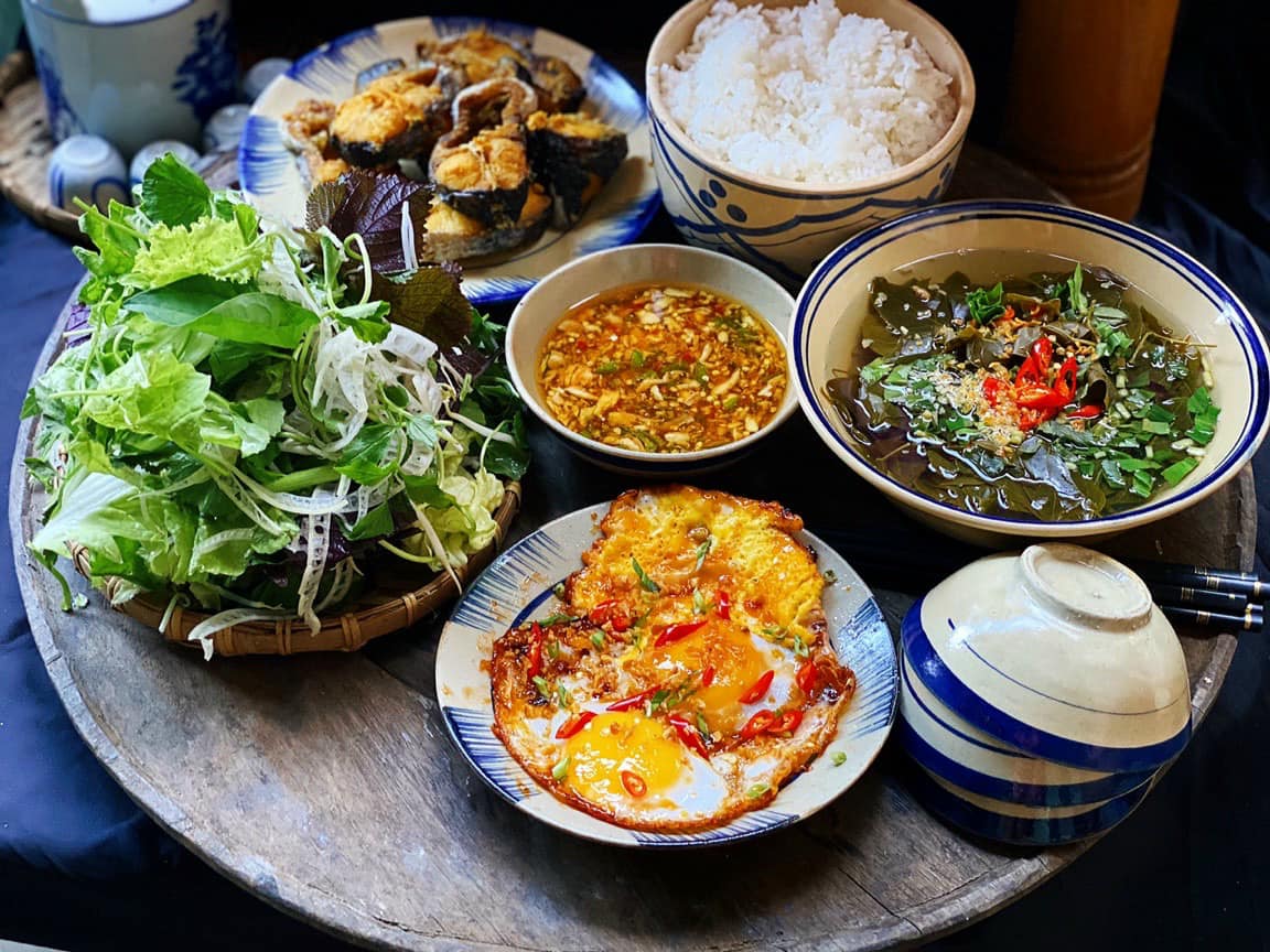 Mâm cơm Việt truyền thống với chén nước mắm Quang Hải chấm cá kho, rau luộc